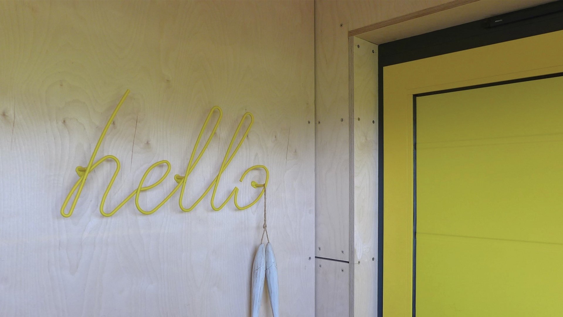 yellow welcome home sign next to bright front door