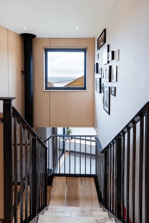 view from top off a staircase looking out of a window towards the beach