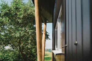 view of black metal clad building showing wooden support posts