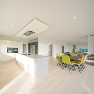 light grey kitchen island with dining table surrounded by green and yellow chairs