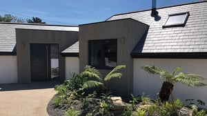 contemporary new build with slate roof and white render