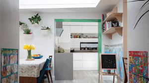 looking through dining room with daffodils on the table into the kitchen