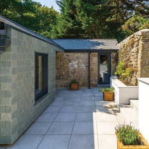 slate hung extension to a stone outhouse with paving around