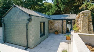 Contemporary natural hung slate rear extension clad set against traditional stone outbuilding