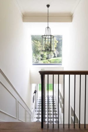 view from landing looking over stairs and through square window to garden
