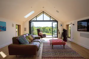 living room looking out of open bifold doors towards the Cornish countryside