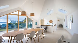 large wooden dining table with eight chairs and a view into sitting room