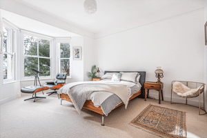 master bedroom with Eames chair in large bay window