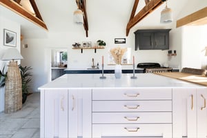 light pink kitchen with white worktop and exposed timber trusses