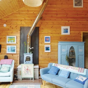horizontal timber wall with light blue wood burner and blue sofa