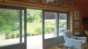 large grey sliding doors opening out to decking and garden beyond