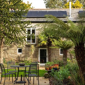 stone farmhouse behind lush foliage