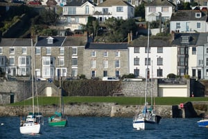 The view of waterfront Falmouth homes from the river with boats anchored in the foreground