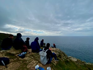 The Marraum architecture team sitting on a cliff overlooking the Cornish sea