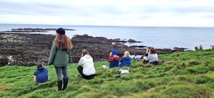 marraum team sitting on grass looking out at sea