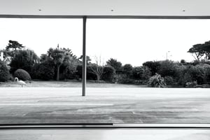 Black and white image of the view from a modern house's back garden, with a beautifully designed veranda