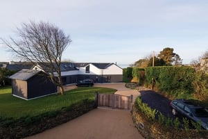 wooden gate with drive leading to white and grey new build